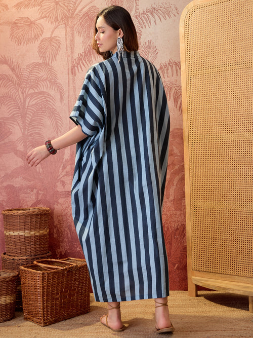 Woman wearing a blue striped oversized kaftan maxi dress with flowing silhouette and vertical stripe pattern.
