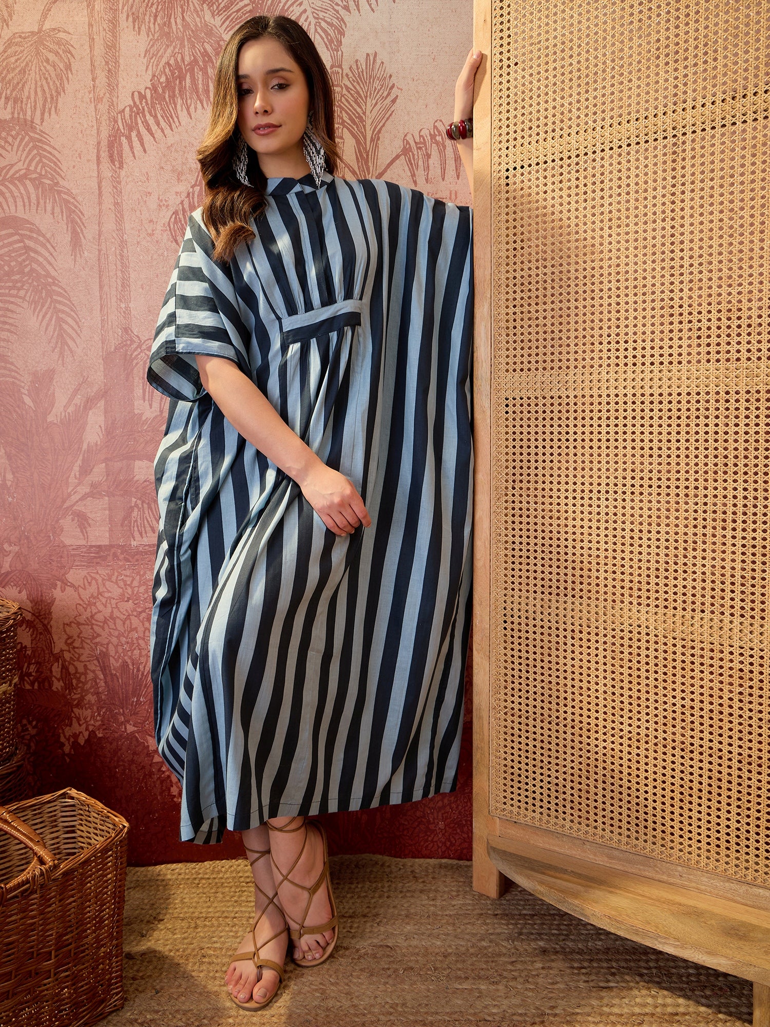 Woman wearing a blue striped oversized kaftan maxi dress with flowing silhouette and vertical stripe pattern.