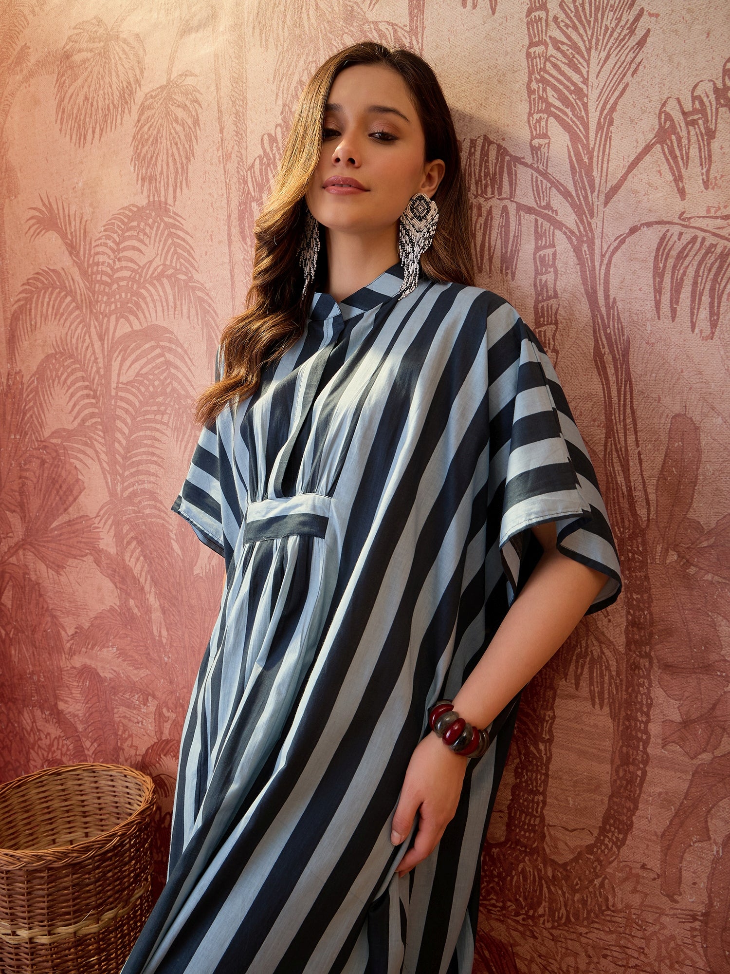 Woman wearing a blue striped oversized kaftan maxi dress with flowing silhouette and vertical stripe pattern.