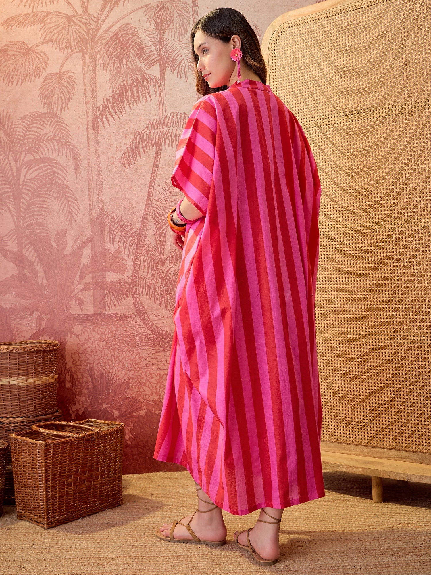 Woman wearing a pink striped oversized maxi kaftan dress with flowing silhouette and vertical stripe pattern.