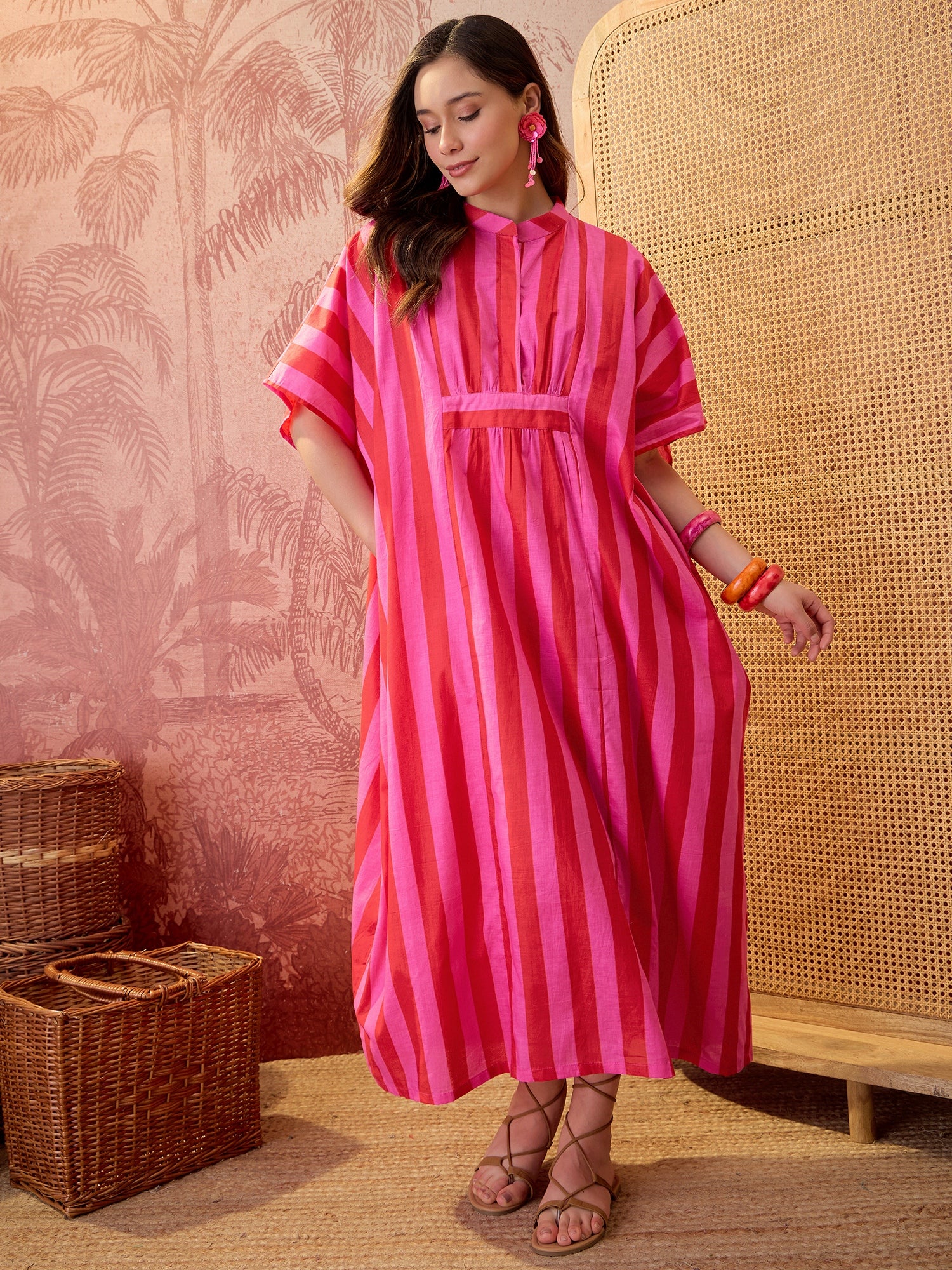 Woman wearing a pink striped oversized maxi kaftan dress with flowing silhouette and vertical stripe pattern.