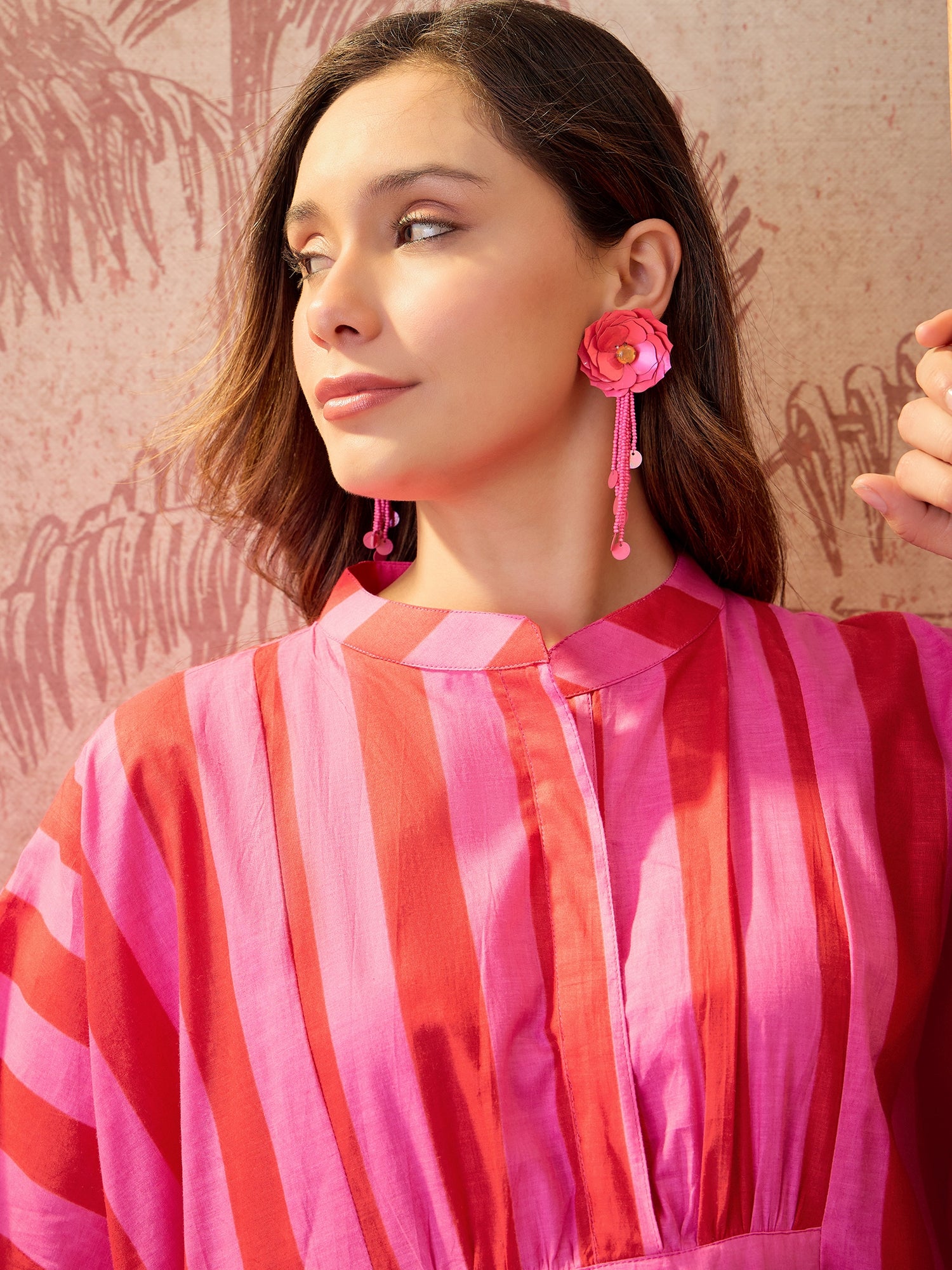 Woman wearing a pink striped oversized maxi kaftan dress with flowing silhouette and vertical stripe pattern.