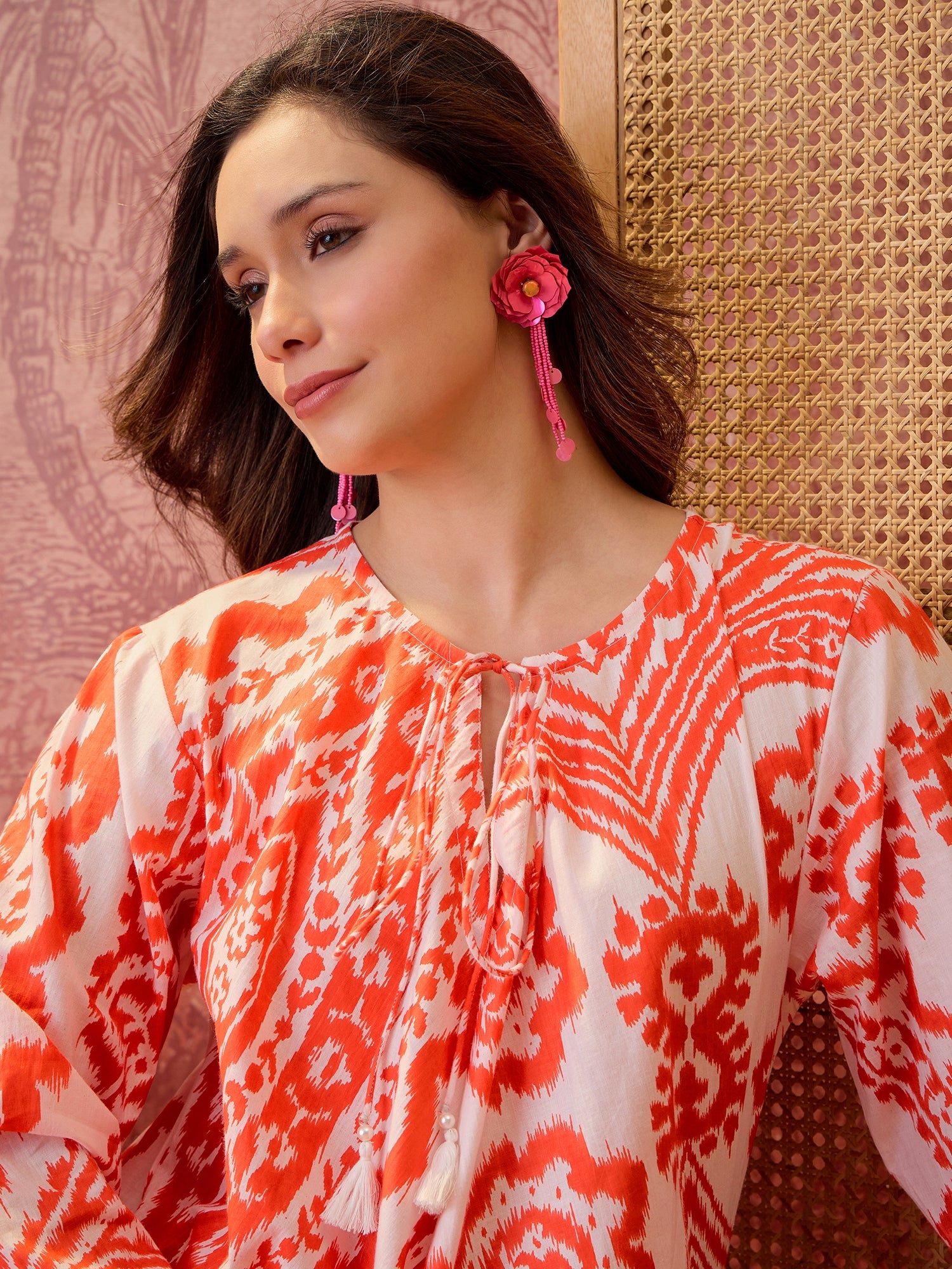 Woman wearing a coral paisley printed relaxed maxi dress with tie-up neckline and flowing silhouette.