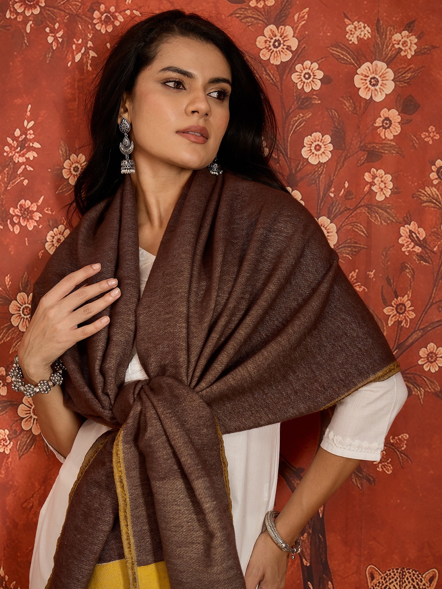 Woman wearing a reversible brown and mustard colorblocked wool blend stole draped over a white kurta, showcasing its soft texture and versatile dual-tone design.