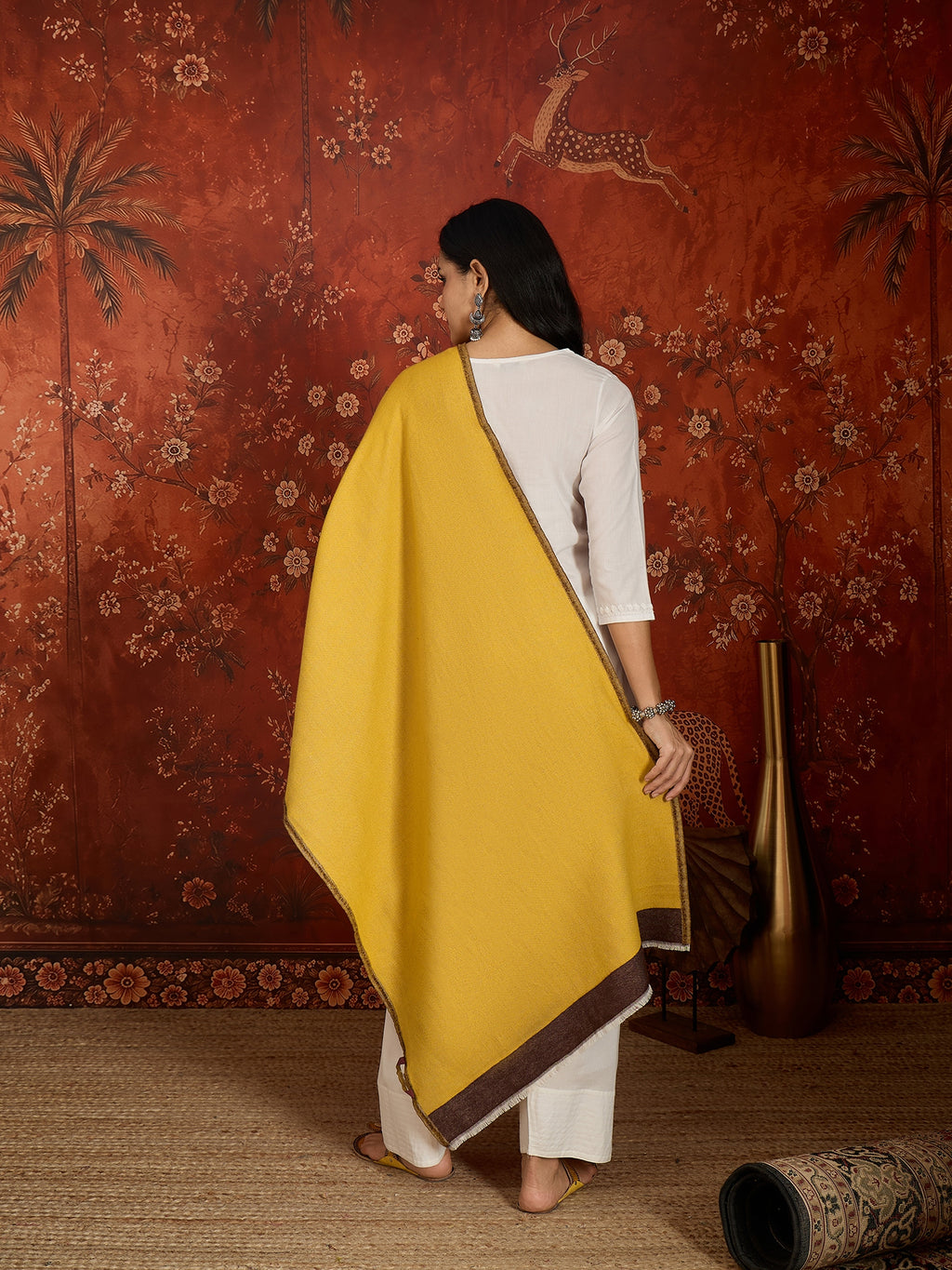 Woman wearing a reversible brown and mustard colorblocked wool blend stole draped over a white kurta, showcasing its soft texture and versatile dual-tone design.