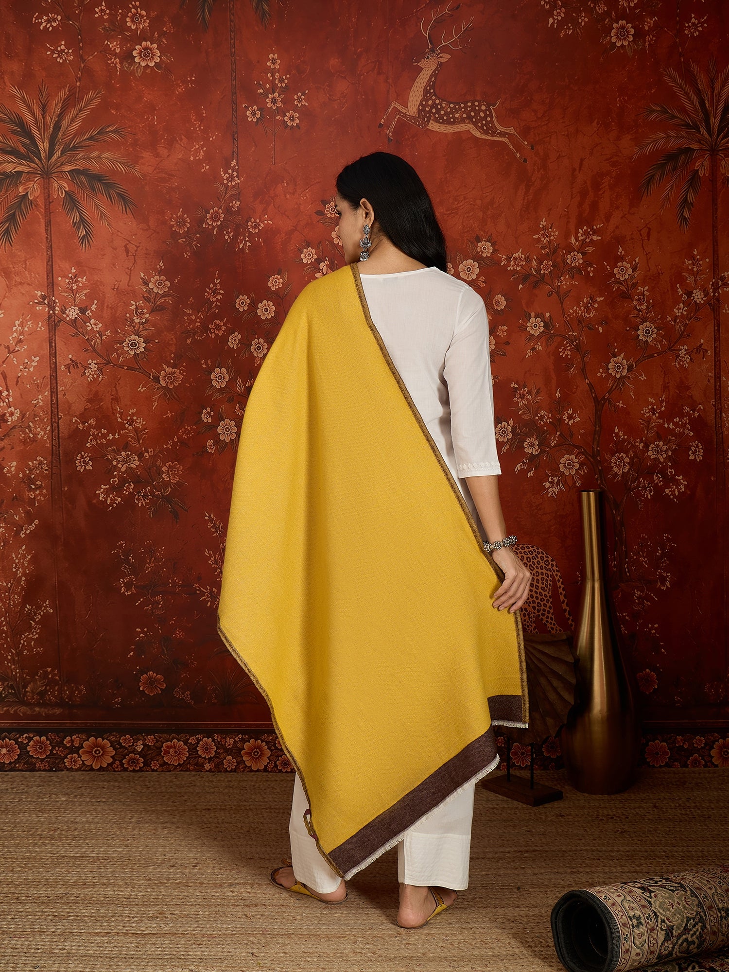 Woman wearing a reversible brown and mustard colorblocked wool blend stole draped over a white kurta, showcasing its soft texture and versatile dual-tone design.