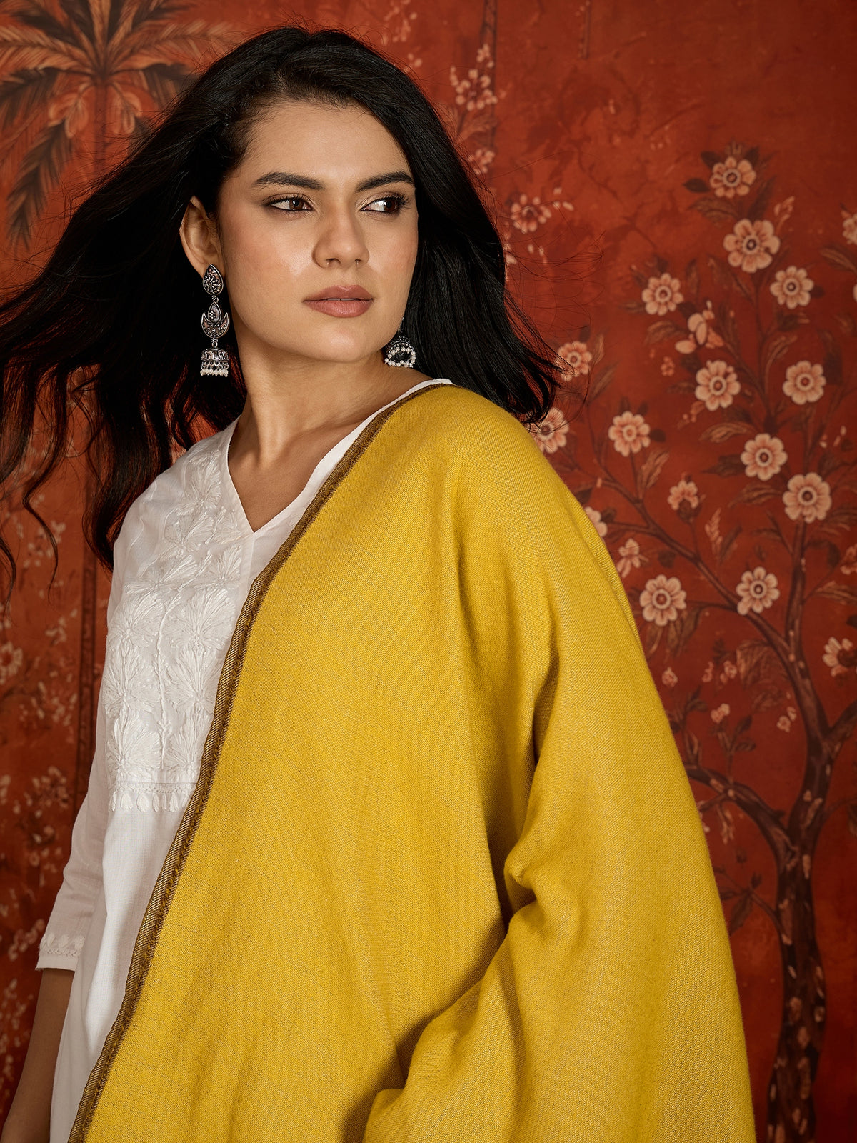 Woman wearing a reversible brown and mustard colorblocked wool blend stole draped over a white kurta, showcasing its soft texture and versatile dual-tone design.