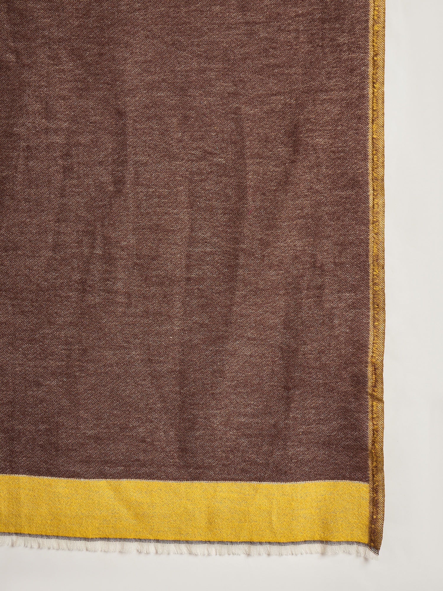 Woman wearing a reversible brown and mustard colorblocked wool blend stole draped over a white kurta, showcasing its soft texture and versatile dual-tone design.