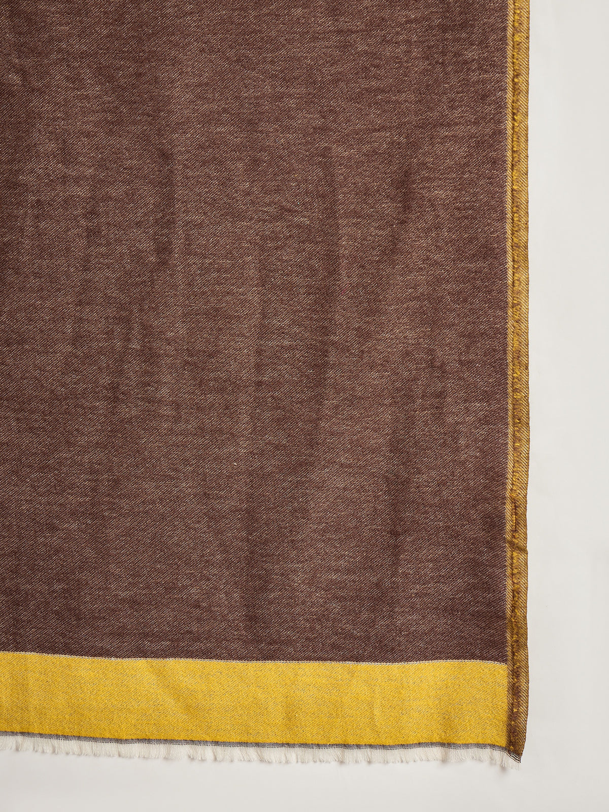Woman wearing a reversible brown and mustard colorblocked wool blend stole draped over a white kurta, showcasing its soft texture and versatile dual-tone design.
