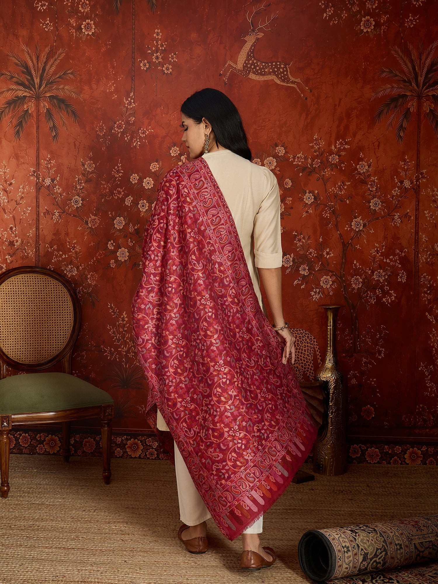 Woman draped in a maroon Kashmiri woven stole featuring intricate paisley and floral jacquard motifs with elegant ornamental borders.