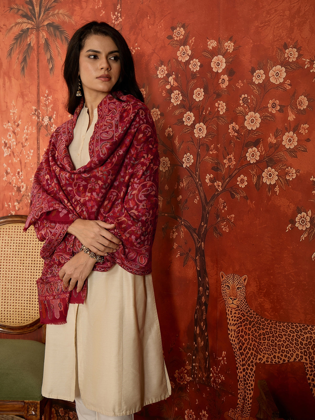 Woman draped in a maroon Kashmiri woven stole featuring intricate paisley and floral jacquard motifs with elegant ornamental borders.