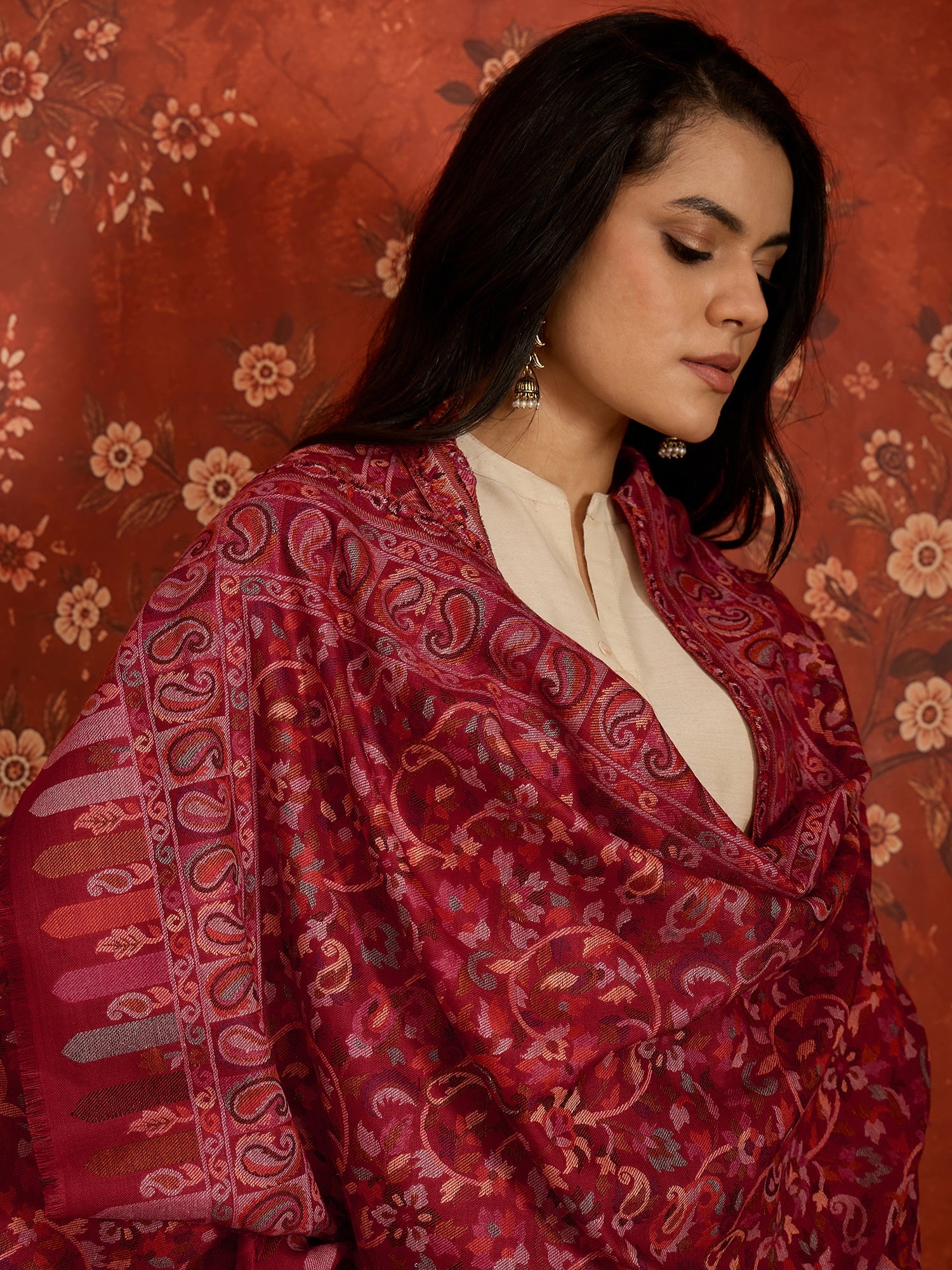 Woman draped in a maroon Kashmiri woven stole featuring intricate paisley and floral jacquard motifs with elegant ornamental borders.