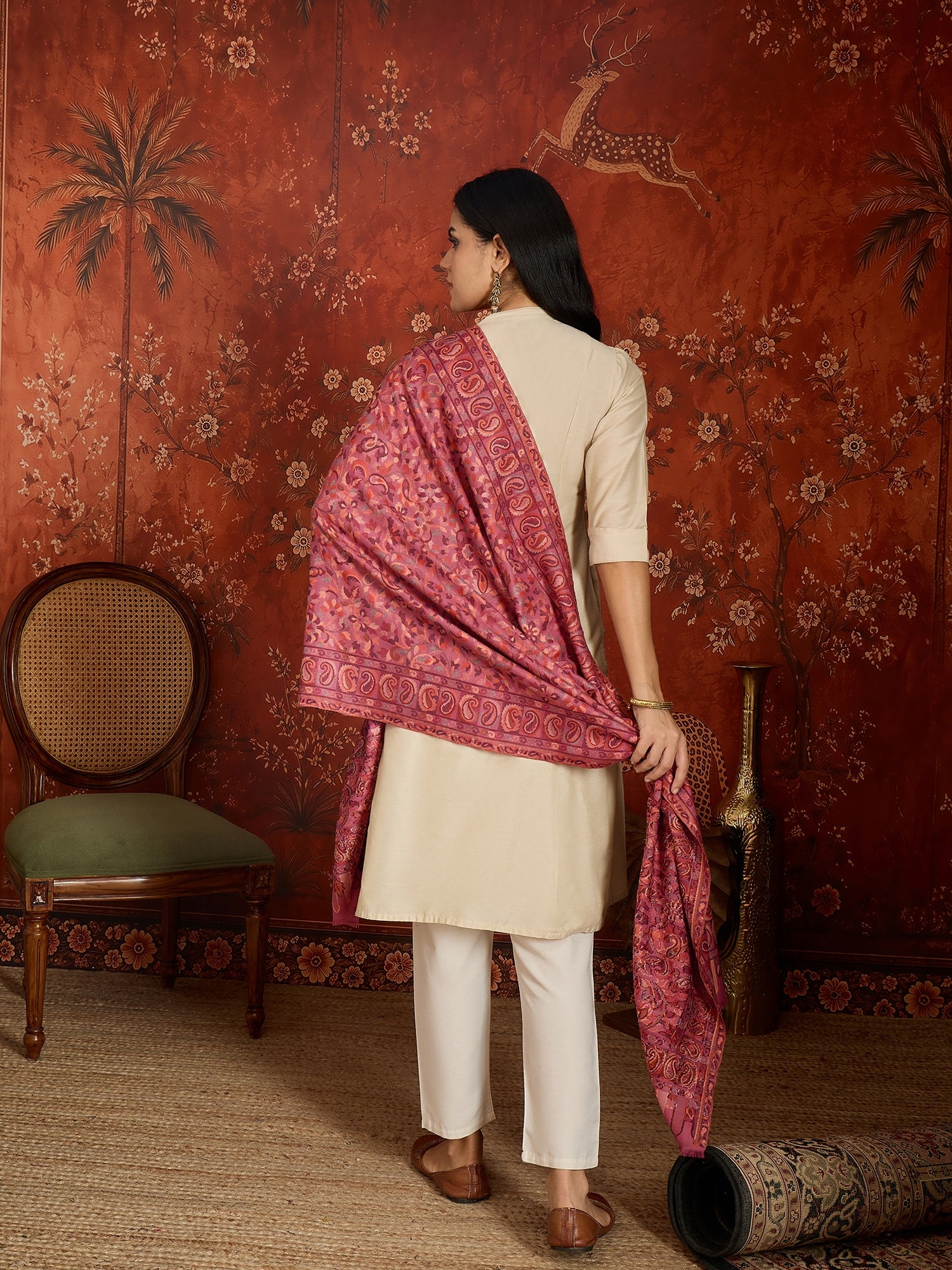 Woman draped in a Gajjari pink Kashmiri Kaani stole featuring intricate woven paisley motifs and traditional jacquard craftsmanship.