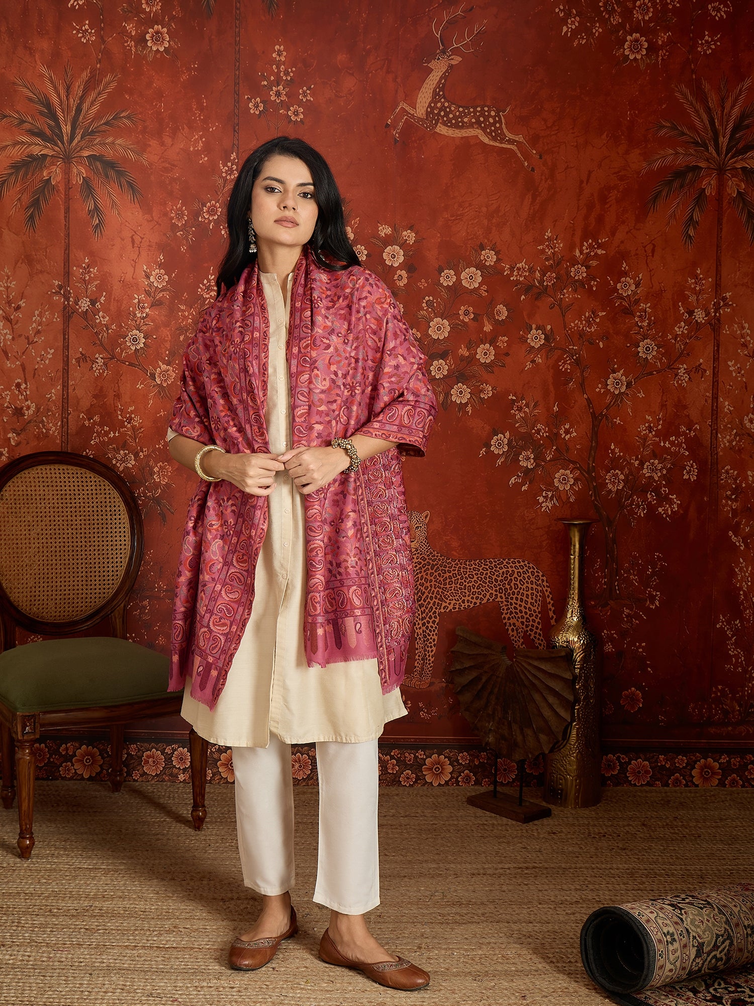 Woman draped in a Gajjari pink Kashmiri Kaani stole featuring intricate woven paisley motifs and traditional jacquard craftsmanship.
