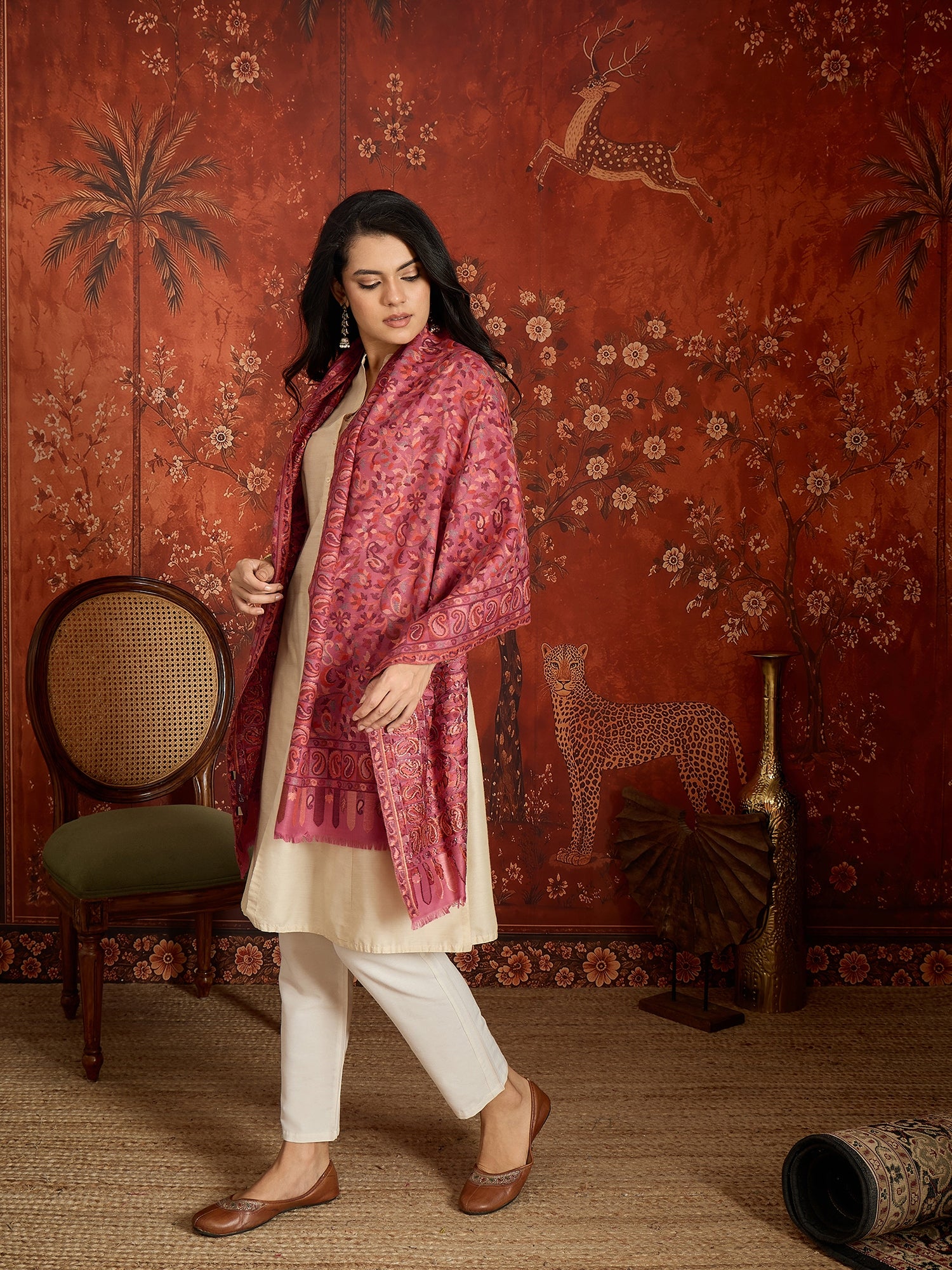 Woman draped in a Gajjari pink Kashmiri Kaani stole featuring intricate woven paisley motifs and traditional jacquard craftsmanship.