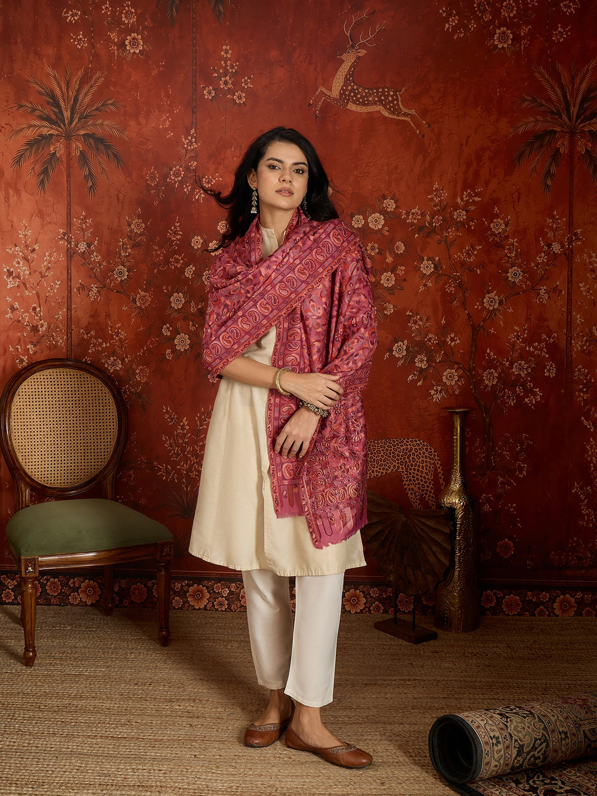 Woman draped in a Gajjari pink Kashmiri Kaani stole featuring intricate woven paisley motifs and traditional jacquard craftsmanship.