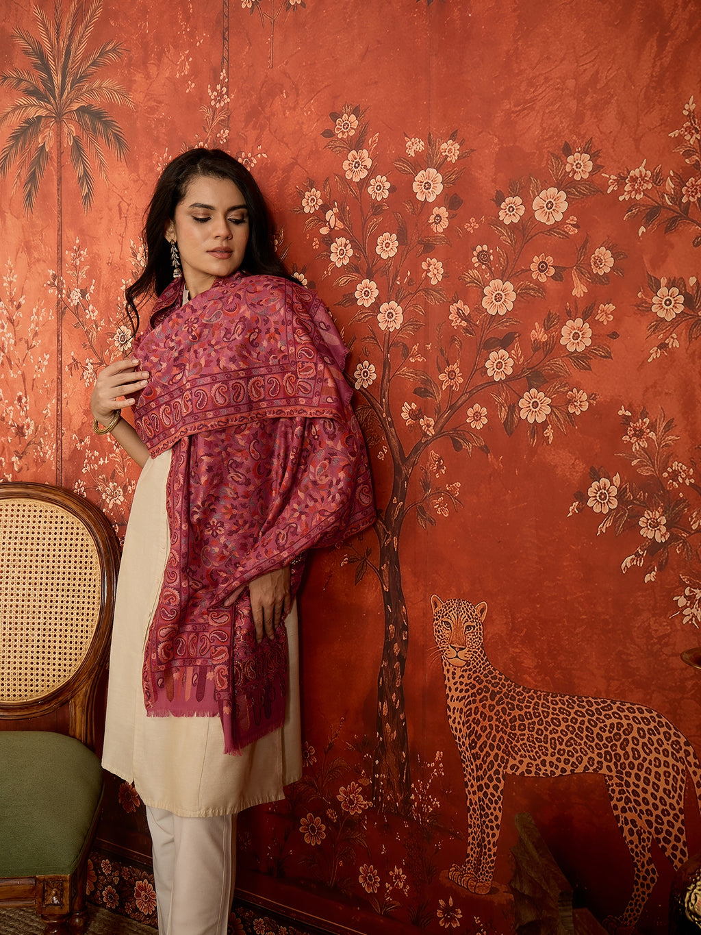 Woman draped in a Gajjari pink Kashmiri Kaani stole featuring intricate woven paisley motifs and traditional jacquard craftsmanship.