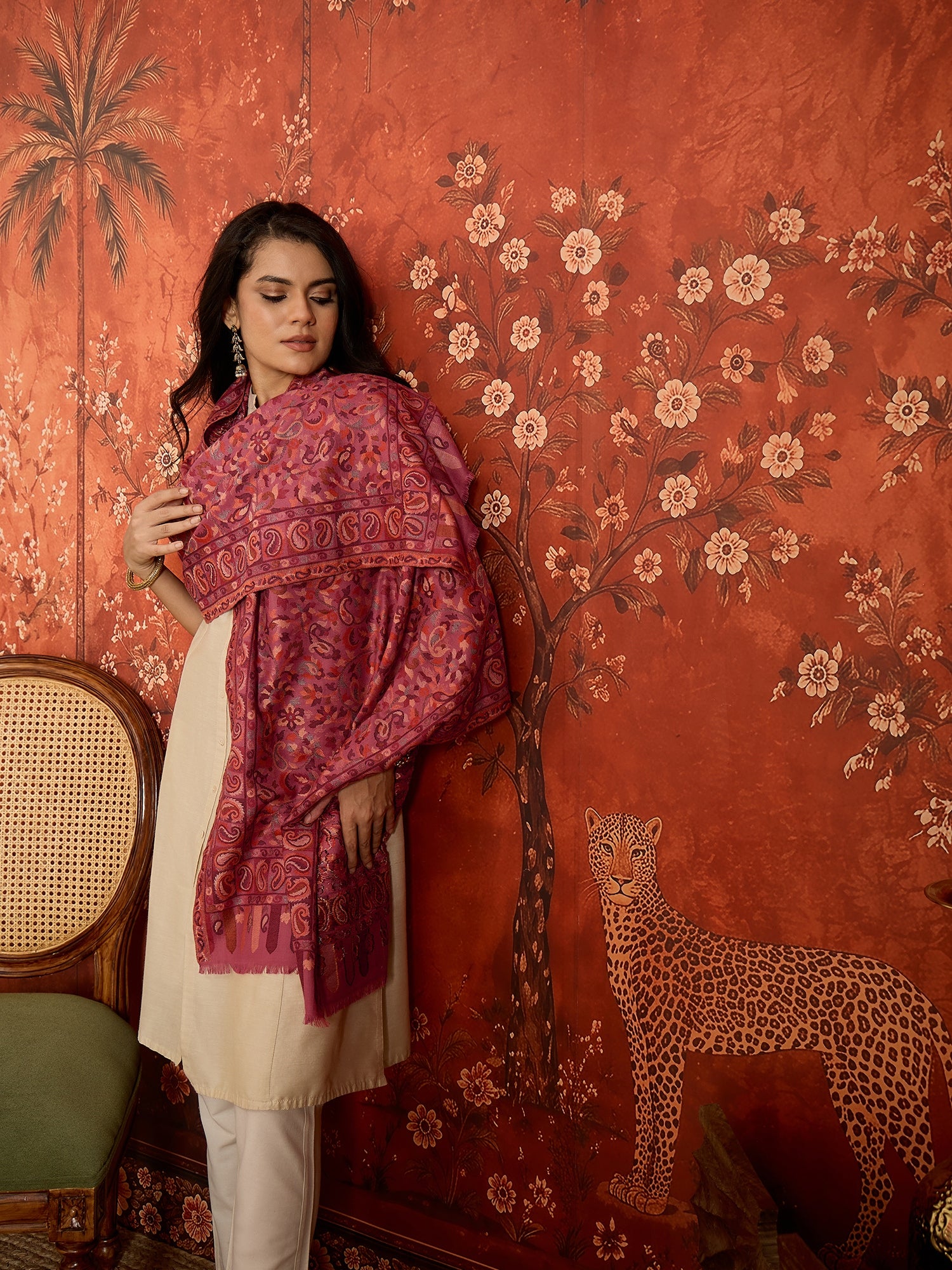 Woman draped in a Gajjari pink Kashmiri Kaani stole featuring intricate woven paisley motifs and traditional jacquard craftsmanship.