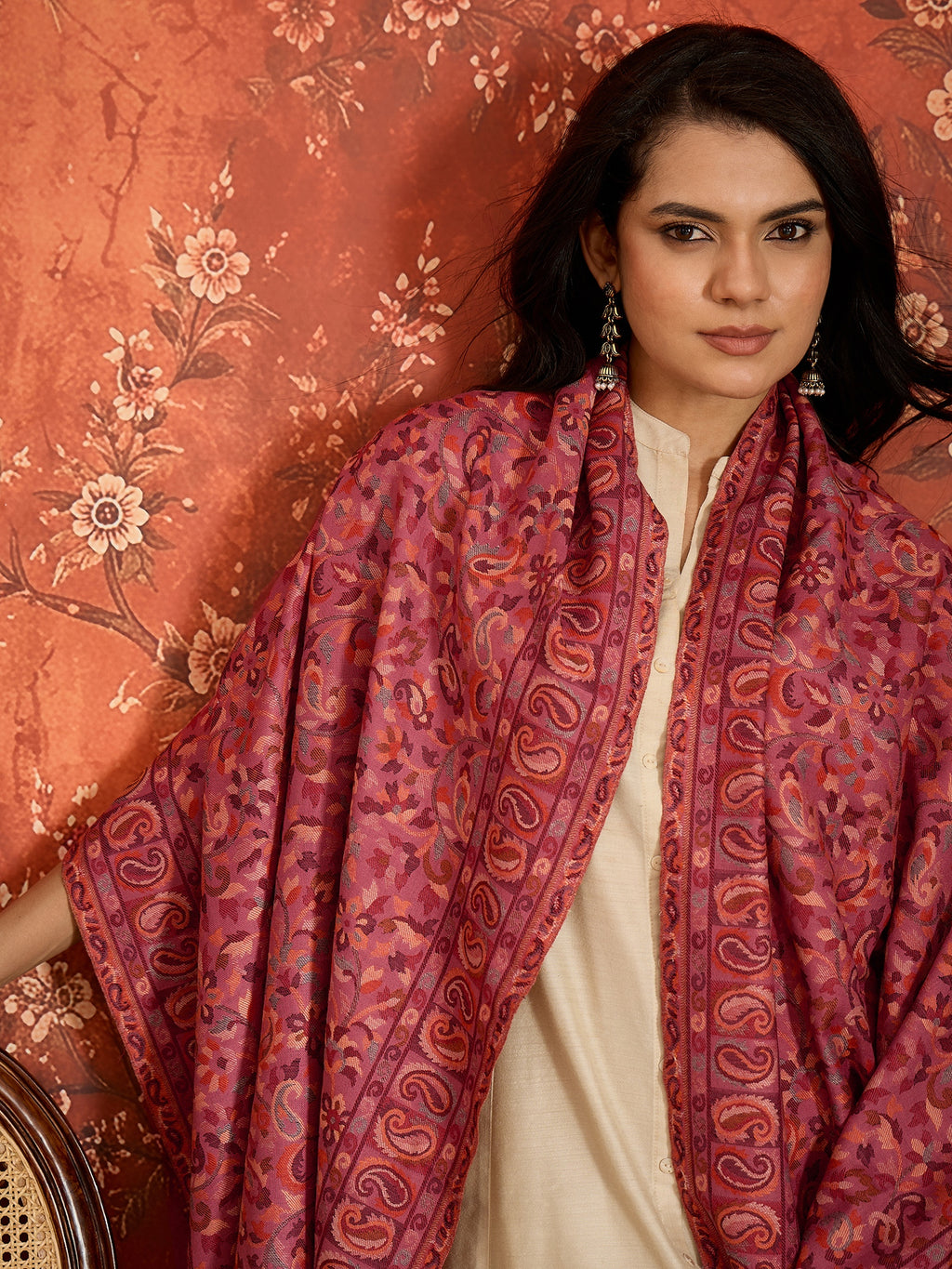 Woman draped in a Gajjari pink Kashmiri Kaani stole featuring intricate woven paisley motifs and traditional jacquard craftsmanship.