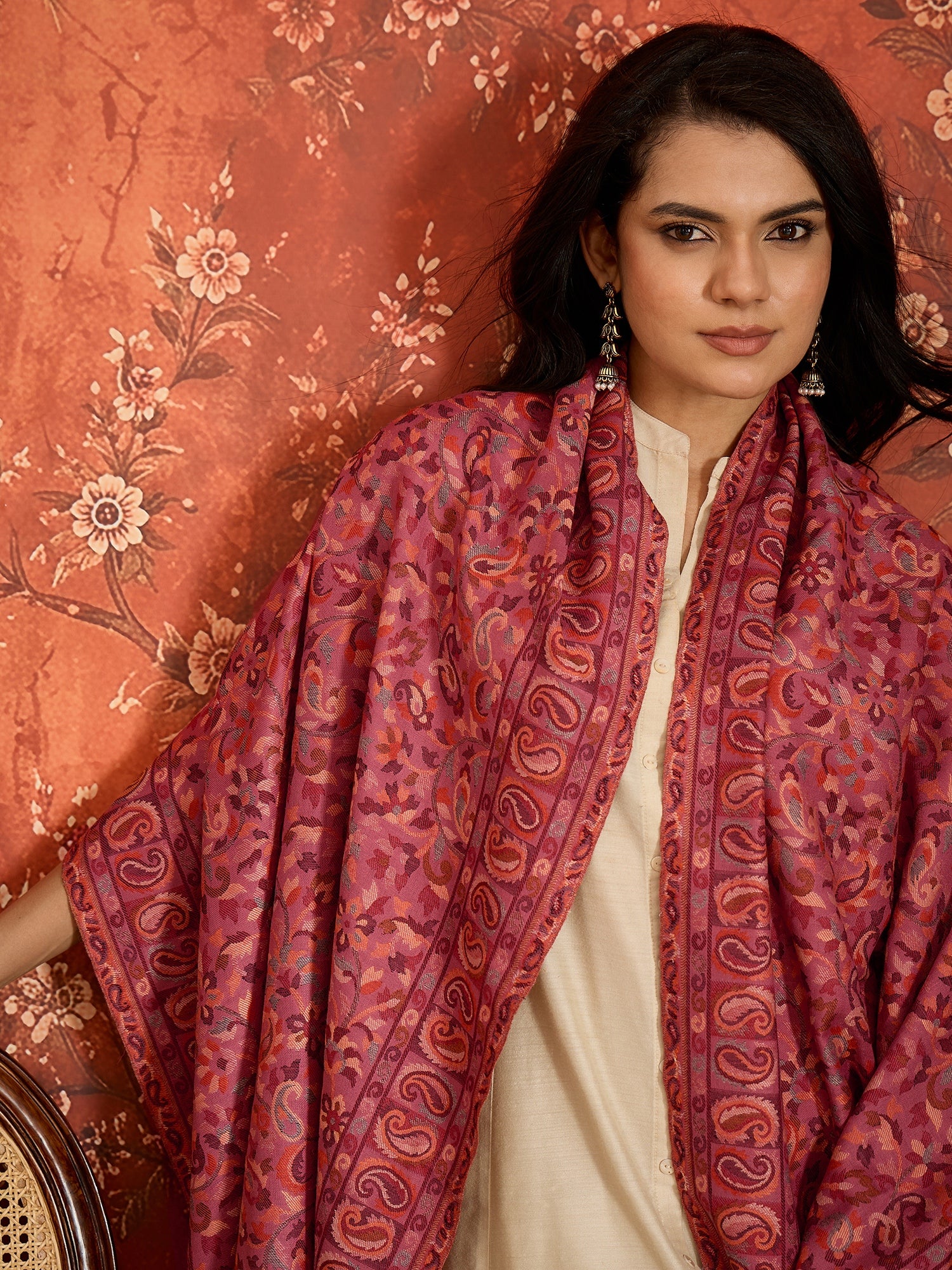 Woman draped in a Gajjari pink Kashmiri Kaani stole featuring intricate woven paisley motifs and traditional jacquard craftsmanship.