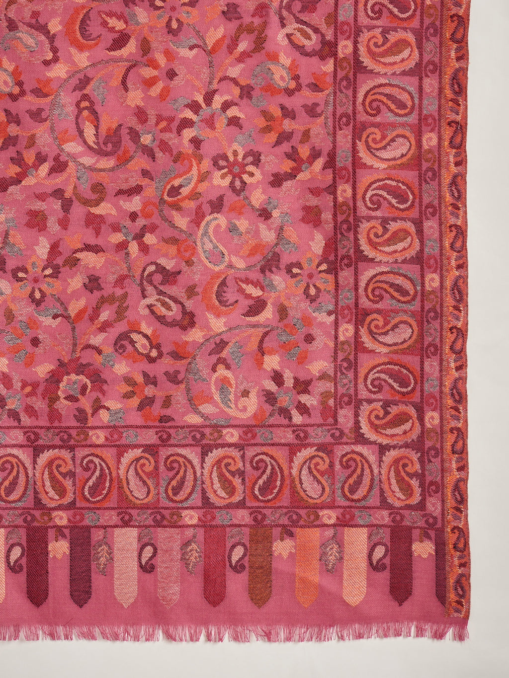 Woman draped in a Gajjari pink Kashmiri Kaani stole featuring intricate woven paisley motifs and traditional jacquard craftsmanship.