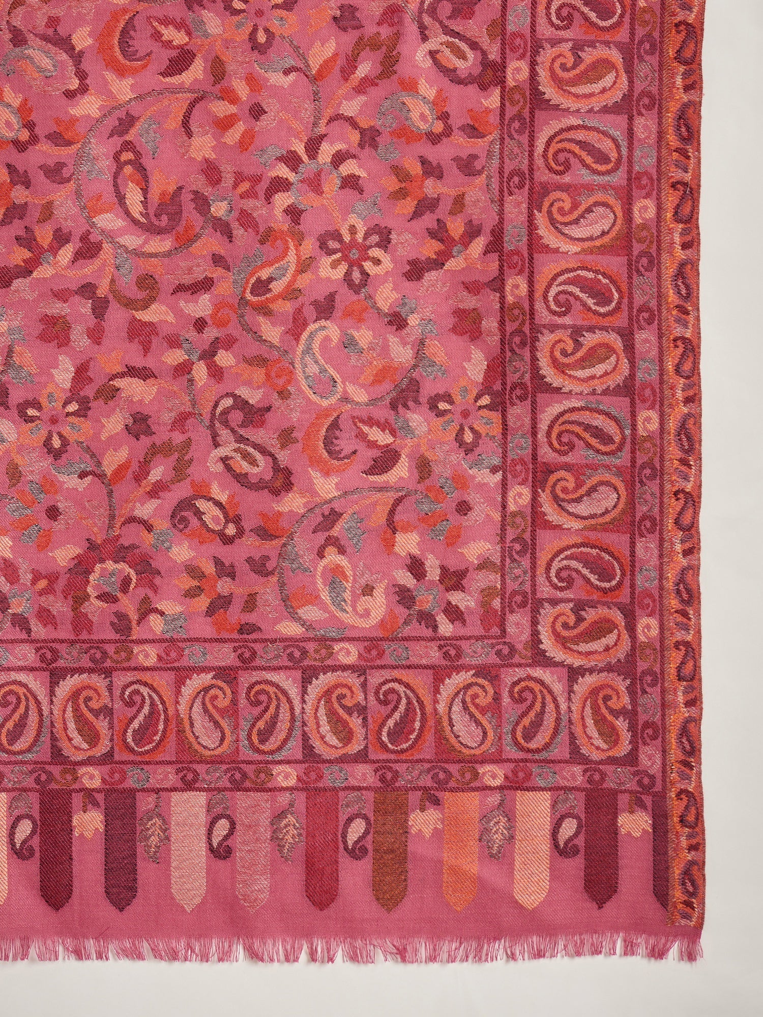 Woman draped in a Gajjari pink Kashmiri Kaani stole featuring intricate woven paisley motifs and traditional jacquard craftsmanship.
